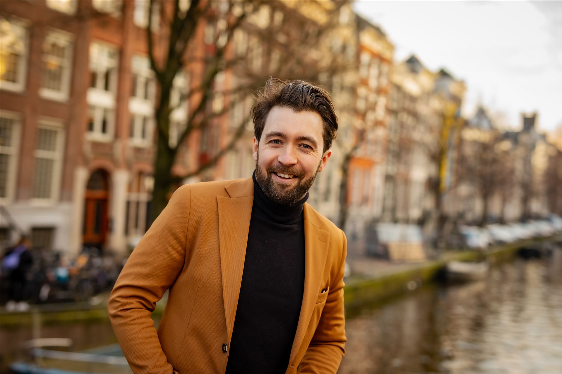 Lochlan Brown, conductor and pianist, standing beside an Amsterdam canal